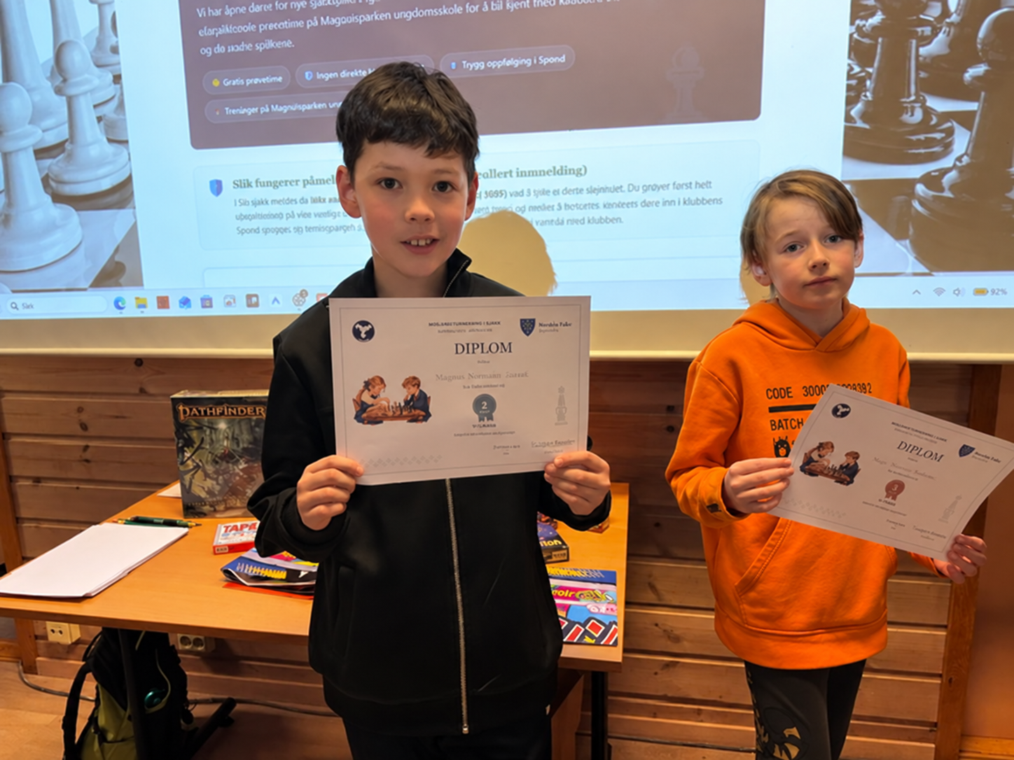To barn med diplomer under premieutdelingen